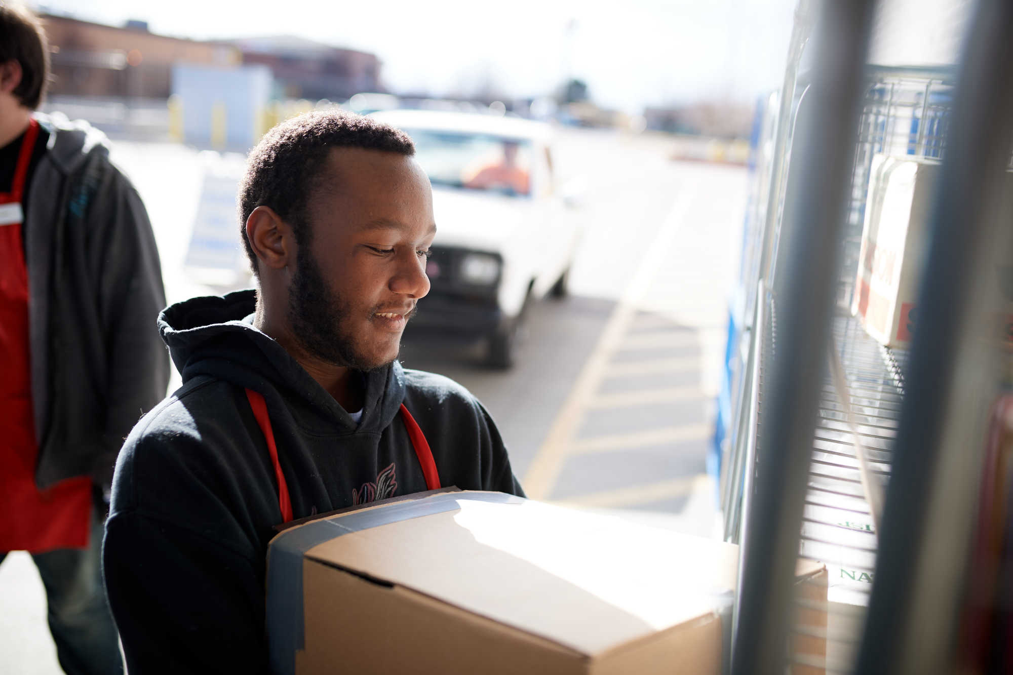 A Deseret Industries associate unloads a box of donated goods from a car.